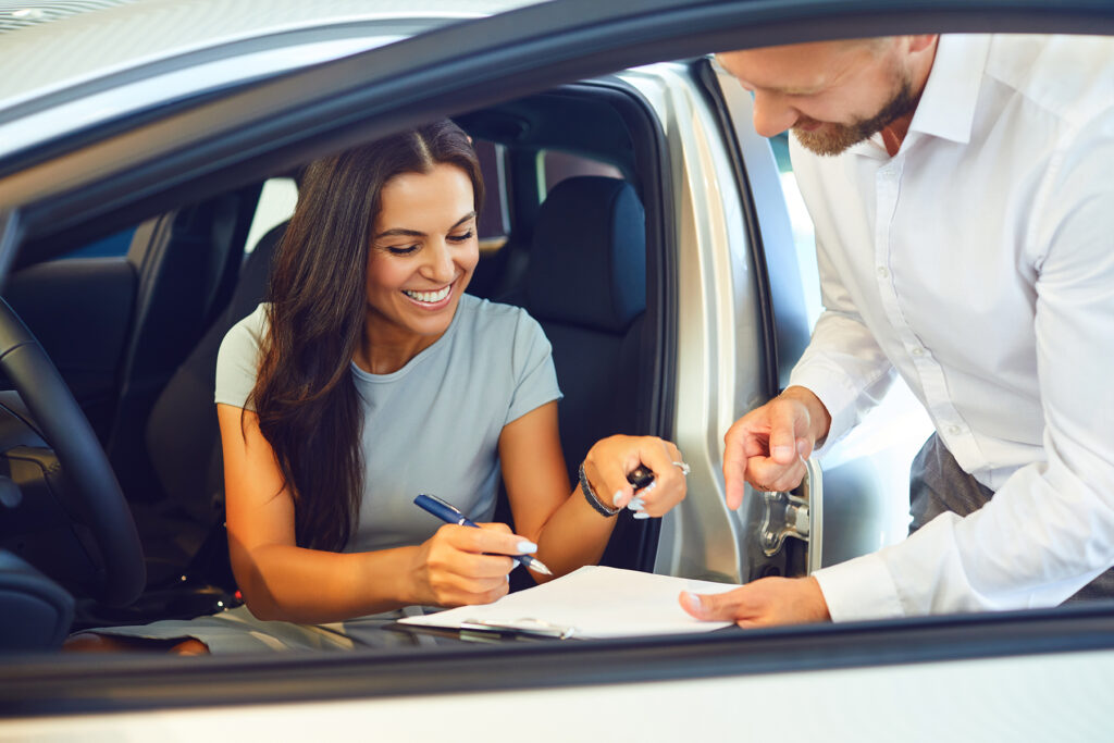 A young woman buys a car in a car showroom